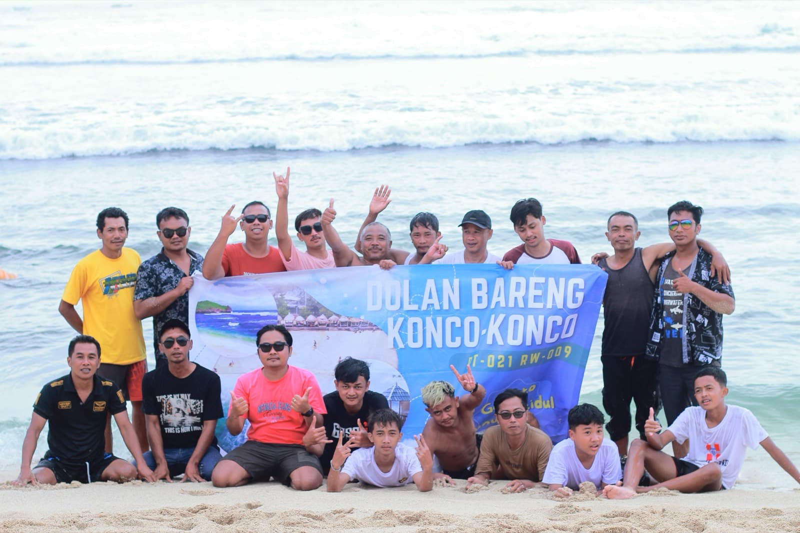 Rombongan berpose di pasir dengan spanduk